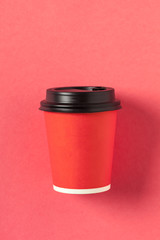 Cardboard red coffee cup on pink background flat lay top view