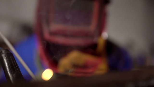 cute welder girl in uniform in the garage working with welding equipment. Women's work in art