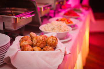 Catering night food arrangement - small breads in a bowl and potato salad in background