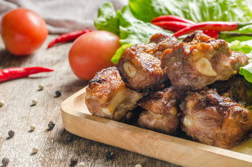 Close up fired pork rips on wooden plate with vegetable