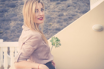 blonde girl with long hair, eyes closed, with blouse and pleated skirt in the terrace breathes...