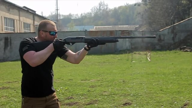 The man in glasses targets and shoots with a shotgun. 50 fps
