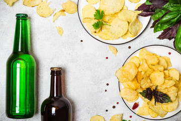 Beer bottles and crispy potato chips on a gray background