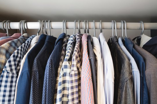 Various shirts hanging in hangers at home