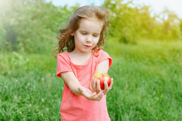 cute baby girl stretches out a red Apple.	
