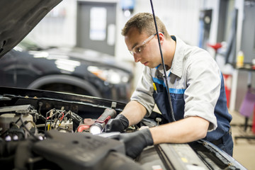 Handsome mechanic job in uniform working on car