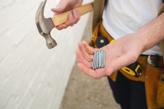 Male carpenter holding hammer and nails