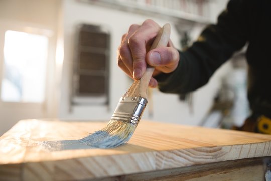 Male carpenter painting a table