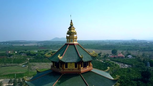aerial round close motion Buddhist pagoda roofs against valley