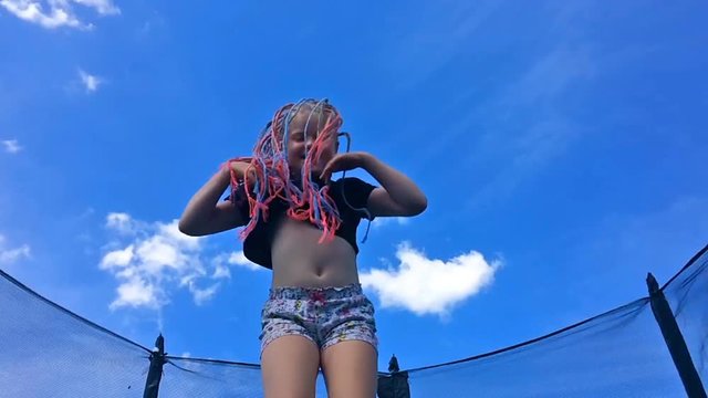 carefree childhood, happy summer. beautiful girl with African pigtails jumping on a trampoline - slow motion