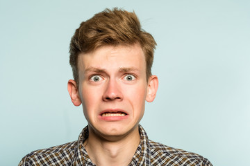 awkward gawky fumbling oafish dorky man facial expression. portrait of a young guy on light background. emotion facial expression. feelings and people reaction.