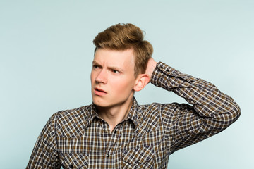 perplexed baffled confused man scratching head and looking owlishly at smth. portrait of guy on light background. emotion facial expression. feelings and people reaction concept.