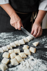 Slow motion of female cook hands cut the dough into pieces with a kitchen knife