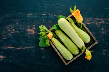 Squash Marrow zucchini in a wooden box on a black table. Top view. Copy space.