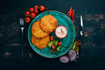 Pancakes with potatoes with sour cream. Potato pancakes. Ukrainian Traditional Cuisine. On a wooden table. Top view. Copy space.