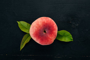 Flat peach with green leaves On a black wooden background. Top view. Free space for your text.