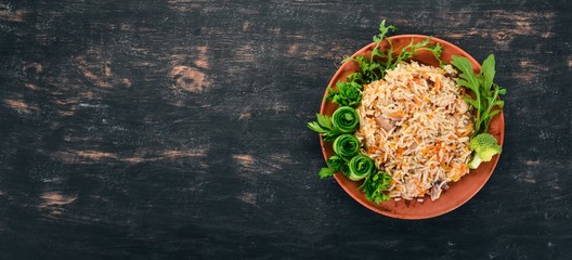 Plov Rice with meat and vegetables on a plate. Uzbek cuisine. On a wooden background. Top view. Copy space.