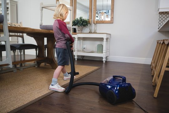 Boy using vacuum cleaner in living room