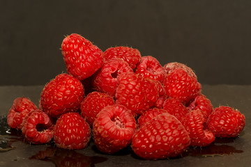 Lot of delicious raspberries on black stone