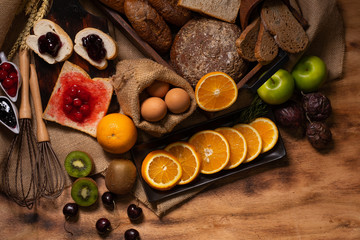 Fruits and bread and eggs as ingredients on wooden table for cooking breakfast with selective focus.