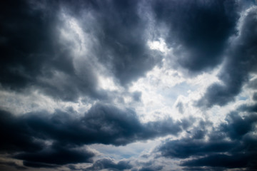 Naklejka na ściany i meble Dramatic dark rain clouds with a blue sky gap.