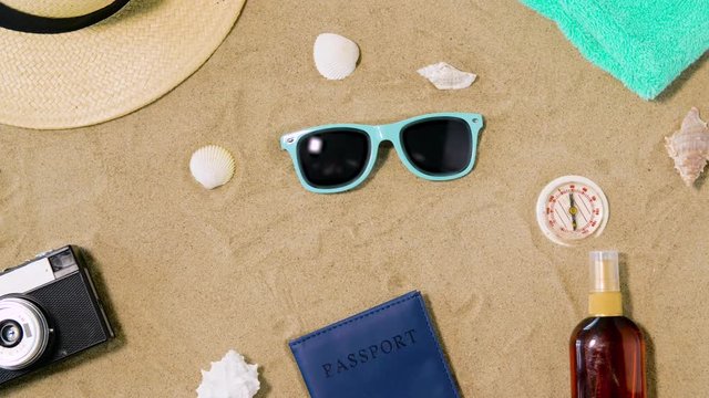 vacation, travel and tourism concept - vintage camera, passport, hat and sunglasses on beach sand