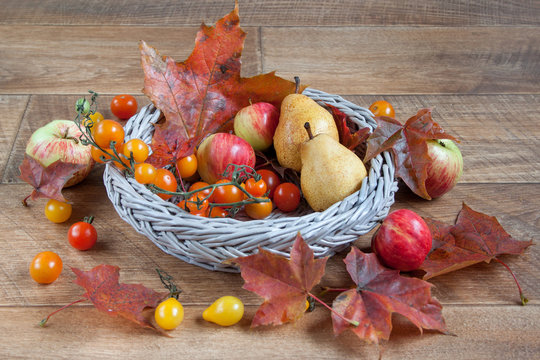 Autumn still life with fruits and autumn leaves are lying in a wicker basket.