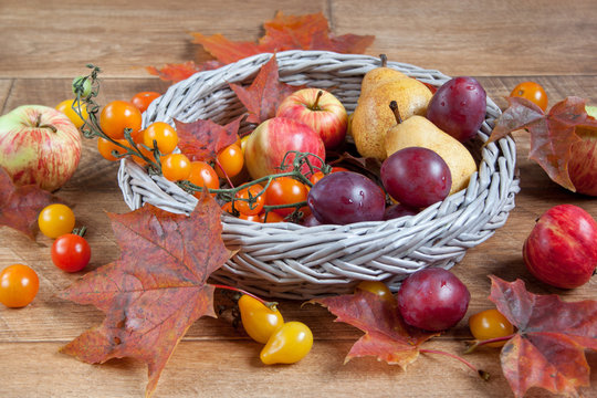 Autumn still life. Various fruits and autumn leaves are lying in a wicker basket.
