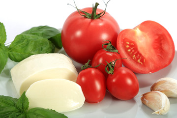 Mozzarella, pomidor, czosnek i bazylia na białym tle.