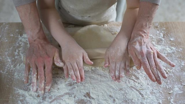 Grandmother and granddaughter rolling dough cooking traditional Christmas dinner