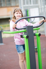 Fototapeta na wymiar teenage girl is engaged in children's exercise equipment