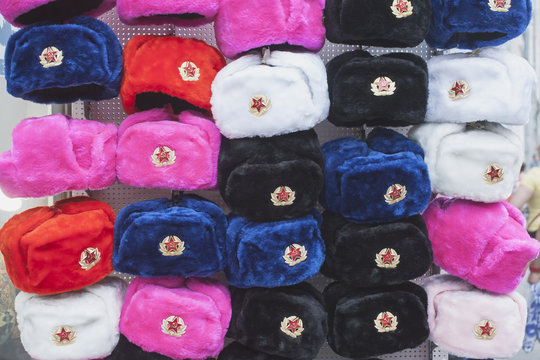 разноцветные меховые шапки-ушанки на витрине сувенирного лотка, фон