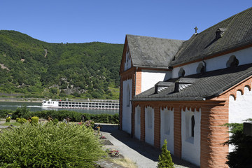 ein flusskreuzfahrtschiff fährt auf dem rhein neben der clemenskapelle bei trechtingshausen