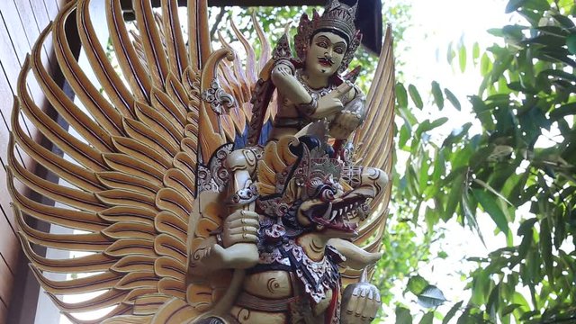Balinese ancient colorful bird god Garuda with wings, close up. Religious traditional statue from wood. Wooden old curved figure of Hindu god in Island Bali, Ubud, Indonesia