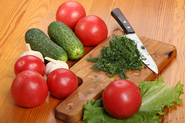 Сutting board with chopped dill leaves and knife on a wooden table