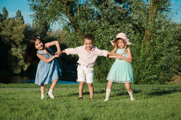 Obraz premium little kids playing around on the lawn. two girls and a boy