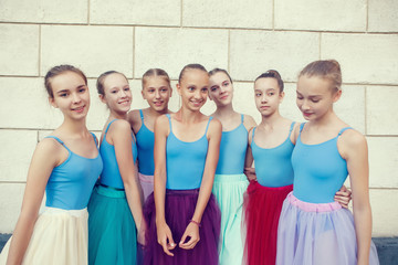 Portrait of ballet dancers talk and hug on street. Young ballerinas in color tutus. Ballet feet on...