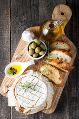 Baked camembert cheese. Fresh Brie cheese and a slice on a wooden board with nuts, honey, rosemary,...