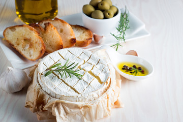 Baked camembert cheese. Fresh Brie cheese and a slice on a wooden board with nuts, honey, rosemary,...
