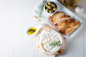 Baked camembert cheese. Fresh Brie cheese and a slice on a wooden board with nuts, honey, rosemary,...