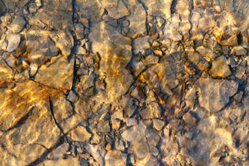 Stones under the water illuminated by the rays of the sun