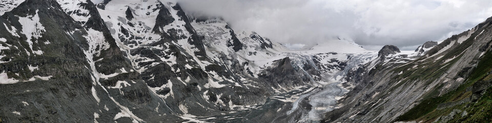 Weites Panorama: links Felswand mit Schnee, rechts Johannisberg schneebedeckt und Gletscher Pasterze in den Alpen von Österreich