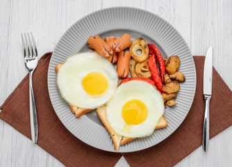Set for breakfast fried eggs, grilled vegetables, sausages. Bread on a wooden table.