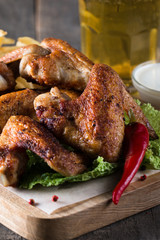 Close-up photo of bbq chicken wings with fries and beer. Barbeques meat with sauces, ketchup, mayonnaise. Fast and junk food concept. 