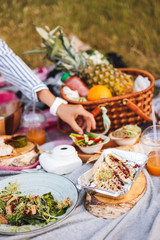 Close up beautiful picnic with variety of tasty food and fruits basket on picnic blanket in city park