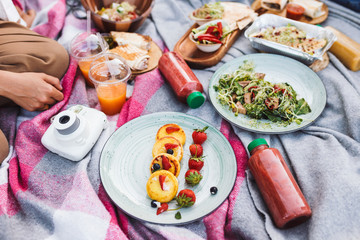 Close up photo of beautiful picnic food and drinks on blanket in city park