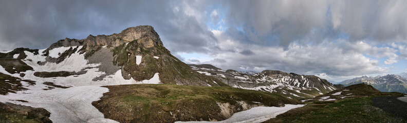 Panoramafoto von rauher Berglandschaft und dramatischen Wolken vor blauem Himmel in den Alpen in Österreich