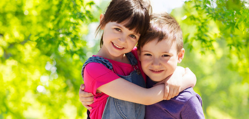 childhood, friendship and family concept - two happy kids hugging over green natural background