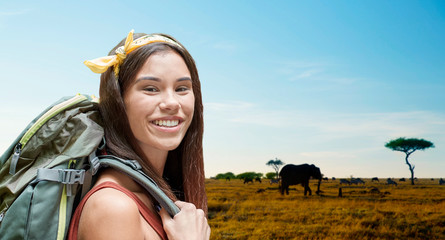 adventure, travel, tourism, hike and people concept - smiling young woman with backpack over animals in african savannah background