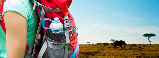 travel, tourism, hike and people concept - close up of woman with water bottle in backpack pocket over animals in african savannah background